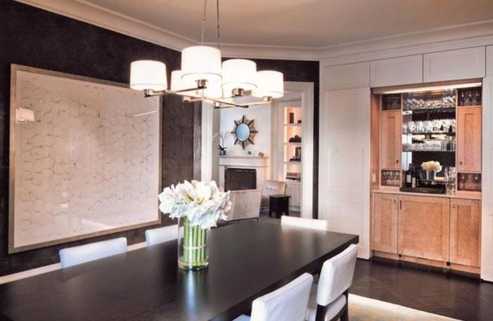 Classic Six — Dining room in dark panelling under a drum-shade chandelier, with the bar joinery visible through the opening