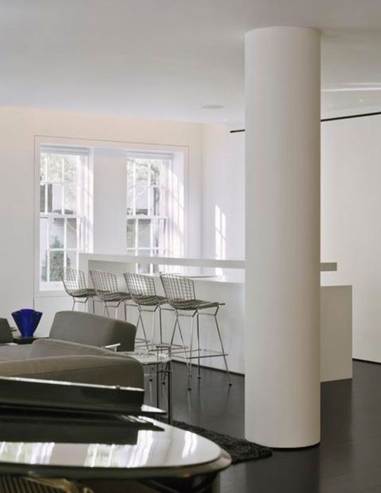 Minimalist Duplex — A rounded structural column carried flush into the ceiling beside the counter, with the window wall left clear