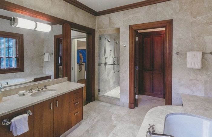 Garden Residence — Bath in travertine with dark walnut casings to the doors and mirror, a walk-in shower at the end of the run