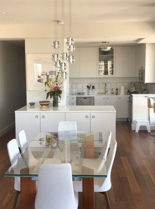 Contemporary Apartment — The dining area and the white kitchen beyond, under a cluster pendant